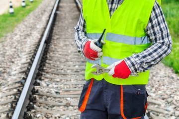 Worker with walkie talkie and wrench on railway