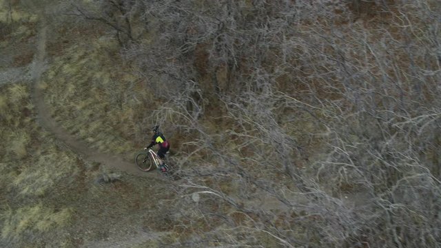 Wide flyover tracking shot of man mountain biking on trail / Cedar Hills, Utah, United States