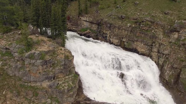 Aerial view of Granite Falls flying backwards over the river and downstream in the Wyoming mountains.
