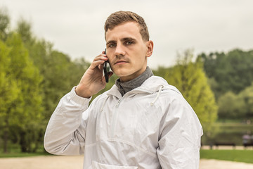 Молодой парень в белой одежде говорит по телефону на...