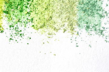 Crumbs  of multicolored chalk, pastels on white paper for watercolor. Yellow,  green, gray, light green crimson. View from above