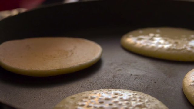 Cooking pancakes on special pan in the kitchen at home. Slow motion. Closeup.