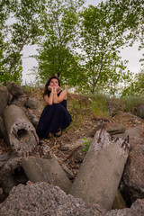 Girl in black dress sitting on the rocks
