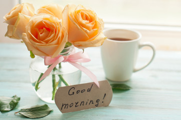 The inscription with a good morning, yellow roses and a cup of coffee or tea, greeting card