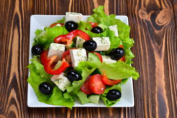 Greek salad on a wooden background. Space for text or design.