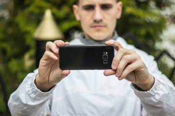 Парень фотографирует на черный телефон