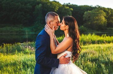 portrait of the bride and groom in nature on a sunny day, a couple in love is kissing in nature