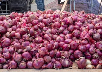 Mound of red onions and shallots for sale at a farmers market