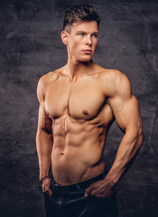 Fototapeta na wymiar Beautiful shirtless young man model with nice muscular body posing at a studio.