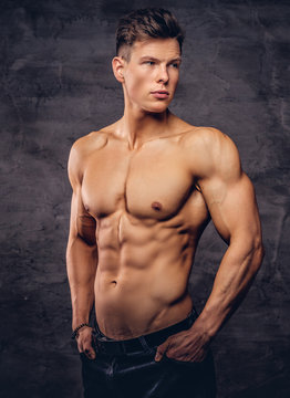 Beautiful shirtless young man model with nice muscular body posing at a studio.