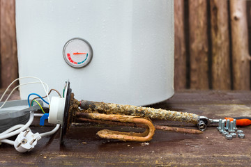 broken water heater with heating elements, on wooden background
