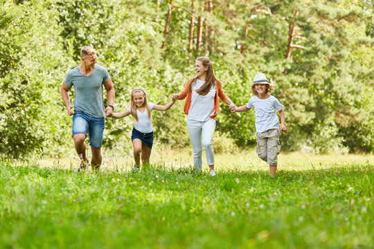 Glückliche Familie und Kinder laufen im Park