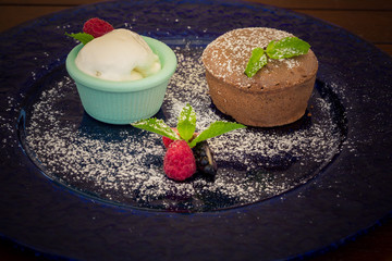 Warm dessert chocolate cake Fondant served on plate with ice-cream, almond chips, mint, icing,...