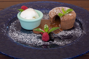 Warm dessert chocolate cake Fondant served on plate with ice-cream, almond chips, mint, icing,...