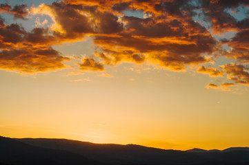 Beautiful dramatic sunrise in the mountains. Landscape with sunlight shining through orange clouds