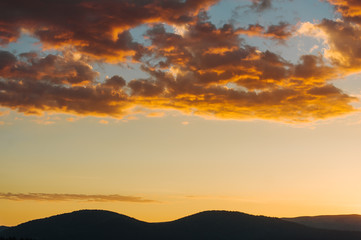 Fototapeta na wymiar Beautiful dramatic sunrise in the mountains. Landscape with sunlight shining through orange clouds