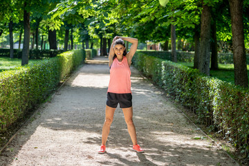 Young attractive latin female stretching before her work out run in a modern park