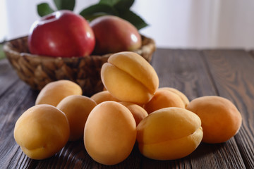 Ripe yellow apricots on a wooden table and apples as background