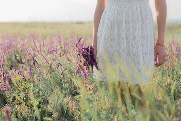 A bouquet of lavender flowers in girl's hands in the field