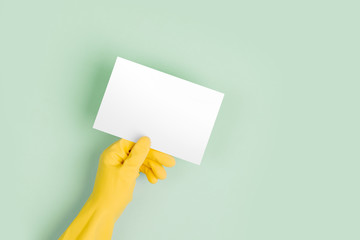 Hands in yellow gloves hold empty card. Cleaning or housekeeping concept background. Copy space. Flat lay, Top view.