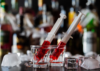 creepy halloween party cocktails with syringes of grenadine syrup as blood, shot drinks at party