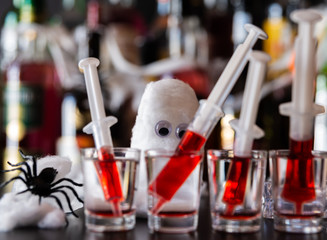 creepy halloween party cocktails with syringes of grenadine syrup as blood, shot drinks at party