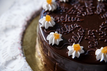 Fototapeta na wymiar Chocolate cake with white flowers from cream close-up.