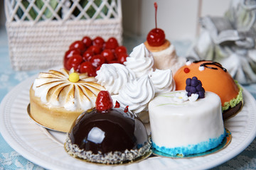 A variety of cakes on a white plate stand on a decorated table.