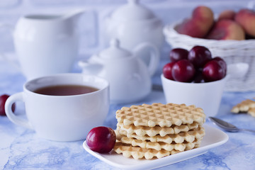 Breakfast. Fika. White cup of tea with thin waffles and lemon jam.