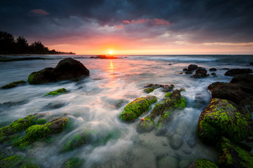 Fototapeta na wymiar Sunset seascape with rocks covered by green moss. beautiful color with dramatic sky.