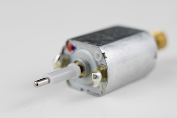 Small electric motor on a white workshop table. Electric drive used in small electrical devices.