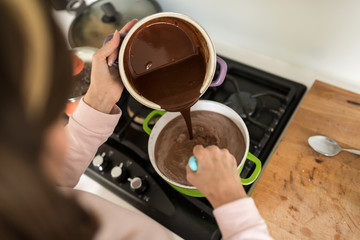 Woman cooking pouring chocolate cream from a pot