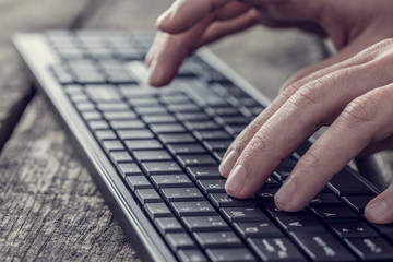 Side view of a man typing on a wireless computer keyboard