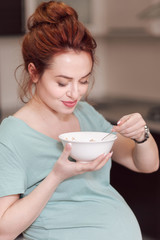 Beautiful pregnant woman eating cereals 