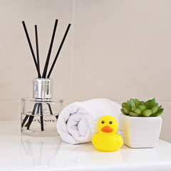 Air fragrant perfumed on sink in the bathroom with white wrapped towel and yellow rubber duck....