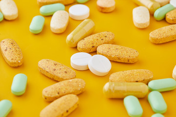 Pills and capsules. Pile of white capsules and redish tablets used as medication or supplements.