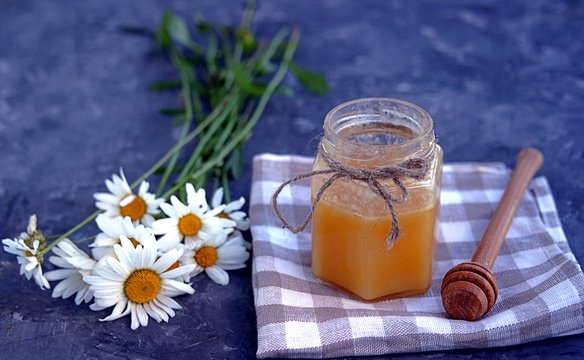 Honey in a jar and a bouquet of chamomiles