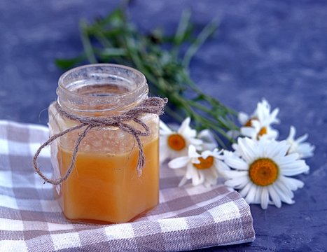 Honey in a jar and a bouquet of chamomiles