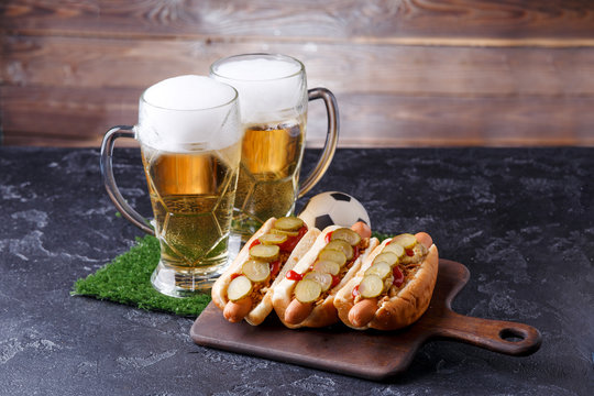 Photo of two mugs with beer, hamburgers on cutting board, soccer ball