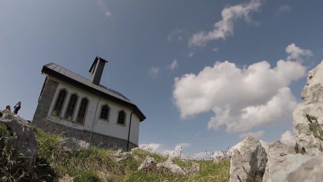 Time lapse (static) with unrecognizable people hiking and clouds moving upon mountain environment