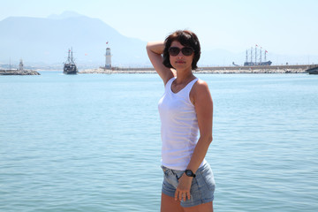 Beautiful girl posing for the camera on the background of the sea. Model posing on the beach at summer day.