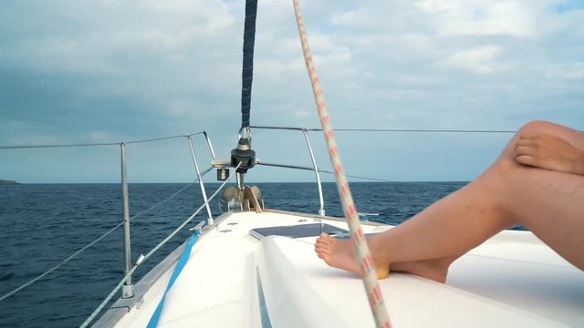 Woman in a yellow hat and blue dress waving hair and smiling on yacht on summer season at ocean. Slow motion