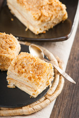 Slices of sweet classic layered cake Napoleon and spoon 