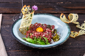 Delicious steak tartare with yolk, capers, green onion and bread