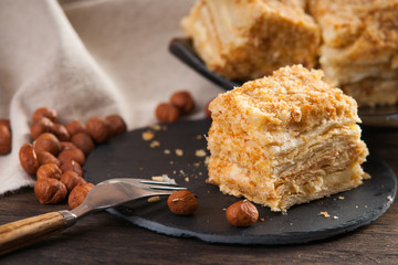 Slices of sweet classic layered cake Napoleon, fork and hazelnuts 