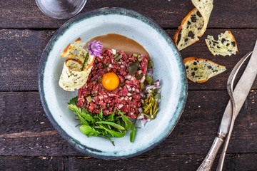 Delicious steak tartare with yolk, capers, green onion and bread
