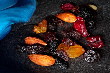 selection of dried fruit and nuts on black slate with blue cloth