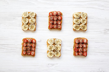 Vegan toasts with peanut butter, fruits and chia seeds over white wooden background, top view. Healthy breakfast, dieting concept.
