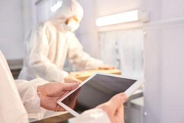 Crop close-up worker hands using tablet pc at sports nutrition production.