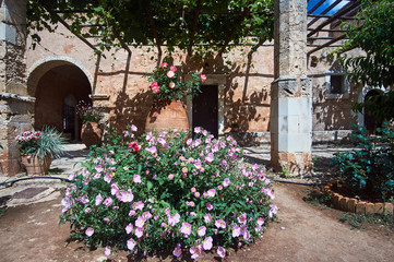 Fototapeta na wymiar Blooming flowers in the courtyard of the historic Orthodox monastery Moni Arcadia on the island of Crete.